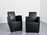pair of black leather chairs in a white room with a white wall