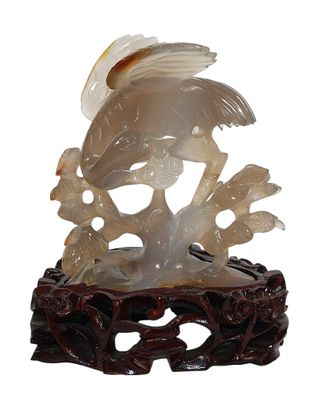 oiseau en jade blanc sculpté sur une branche fleurie, sur fond blanc