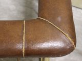 a close up of a brown leather chair with a rope on it