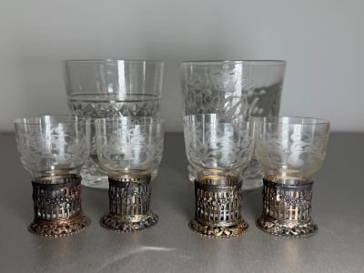 four glasses and a cup on a table with a silver base