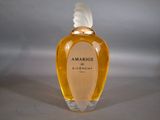 an image of a bottle of perfume with a white feather on top