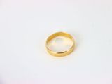 gros plan d'une bague en or sur une surface blanche