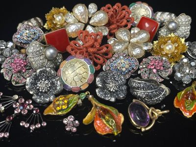 un tas de broches et autres bijoux posés sur une surface noire
