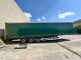 a green semi trailer parked in front of a building