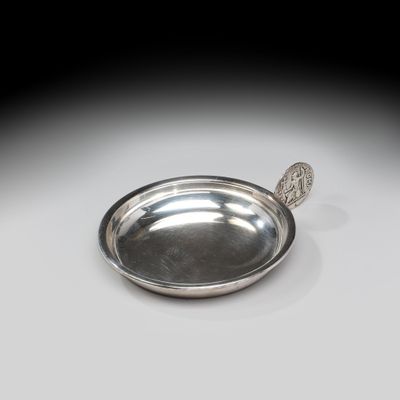 une assiette en argent posée sur une table, avec une cuillère dedans