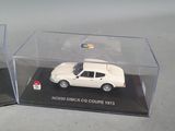 two models of a white car in a display case