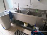 two sinks in the kitchen with buckets and a trash can