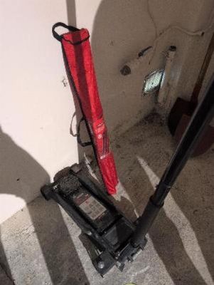 a red umbrella sitting on the floor next to a floor jack