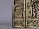 carvings of a couple of people in a wooden frame on a gray surface
