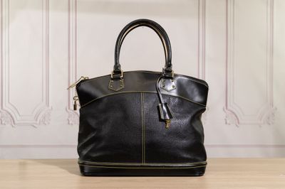 le sac à main en cuir noir est posé sur une table devant un mur