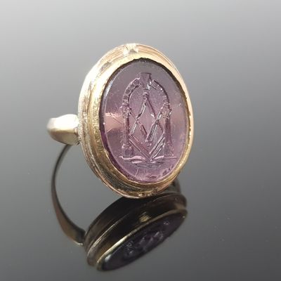 a close up of a gold ring with a purple stone in the center