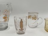 trois verres et un pichet posés sur une surface blanche