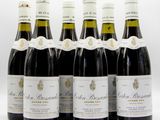 six bouteilles de vin sont alignées sur une surface blanche