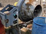 a cement mixer sitting next to two barrels in a yard