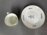 two cups and saucers with blue flowers on them sitting on a table