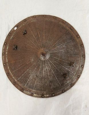 une plaque métallique sur laquelle est représenté un motif en rayons de soleil