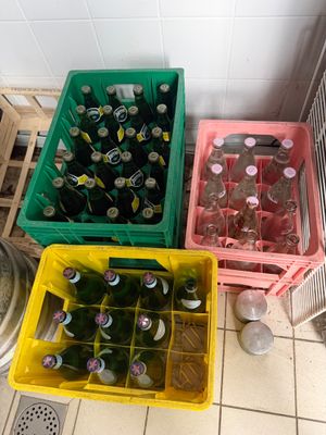 de nombreuses bouteilles de bière dans des récipients en plastique, posées par terre