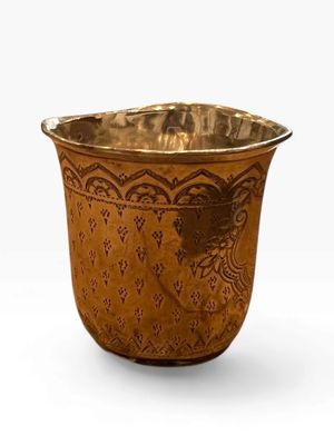 a gold cup with a design on it on a white surface