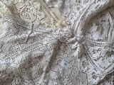 deux vêtements blancs au crochet posés sur un lit
