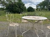 four chairs and a table in the middle of a gravel road