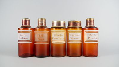 quatre bouteilles contenant un liquide de couleur orange, posées les unes à côté des autres sur une surface blanche