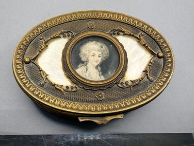une assiette ancienne en or plaqué représentant le portrait d'une dame en robe blanche