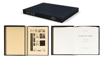 an open book sitting on top of a white table next to a black book