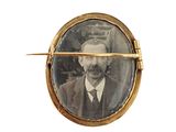 a picture of a man in a suit and tie in a gold broochle