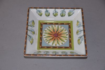 une assiette carrée ornée d'une fleur, posée sur une table
