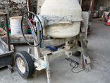 une bétonnière rangée dans un garage, dont une roue repose sur un chariot