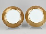 pair of gold and white plates on stands on grey background