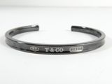 un gros plan sur un bracelet manchette noir portant l'inscription « t & co »