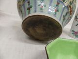 a green bowl sitting next to a vase on a table
