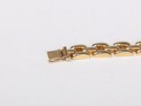 a close up of a gold plated bracelet on a white surface