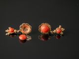 a pair of coral and gold earrings on a black surface