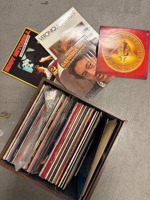 une boîte remplie de disques vinyles posée par terre