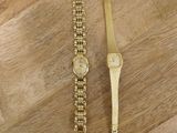 deux montres en or posées sur une surface en bois, avec un plancher en bois