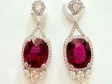 deux paires de boucles d'oreilles en rubis et diamants posées sur un fond blanc