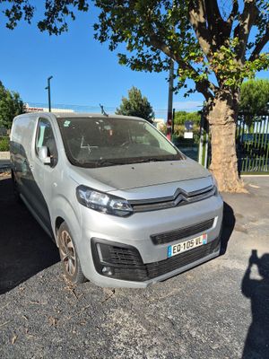 La camionnette est garée sur le parking, à côté d'un arbre.