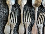 six cuillères en argent et deux fourchettes sont alignées sur une table