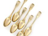six gold spoons with engraved names on them on a white surface