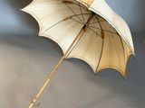a white umbrella with a wooden handle on a gray surface