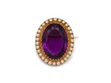 un gros plan sur une bague ornée d'une pierre violette et d'une perle