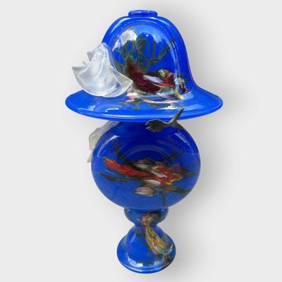 un vase bleu surmonté d'un oiseau