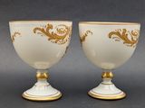 two white and gold vases sitting on top of a table