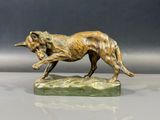 statue en bronze représentant un chien courant sur un rocher posé sur une table