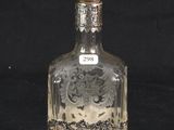 a glass bottle with a silver lid on a black background