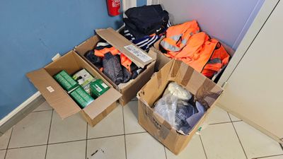 des cartons contenant des vêtements et d'autres objets posés par terre