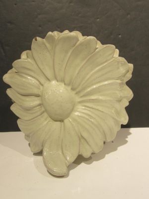 a white vase with a flower on it sitting on a table
