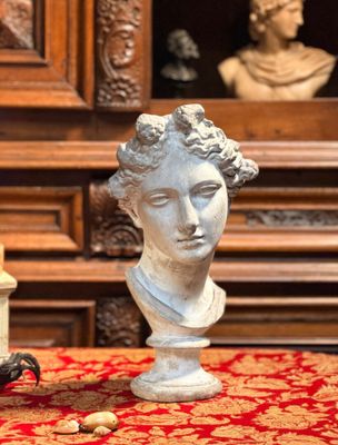 une statue représentant une femme assise sur une table, à côté d'une bougie